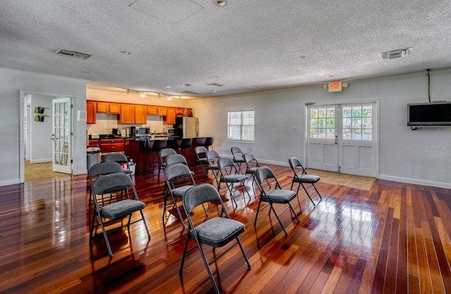 living room featuring hardwood / wood-style floors, crown molding, french doors, and a textured ceiling