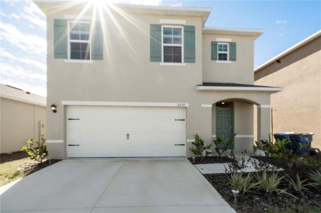 view of front of home with stucco siding, an attached garage, and concrete driveway