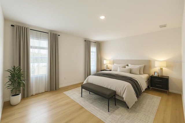 bedroom featuring light wood finished floors, multiple windows, and baseboards