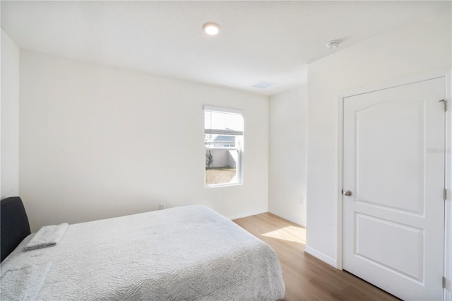 bedroom featuring baseboards, visible vents, and wood finished floors