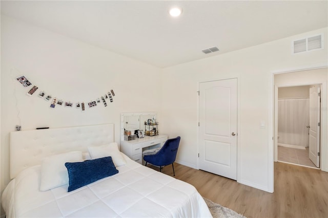 bedroom featuring baseboards, visible vents, and wood finished floors