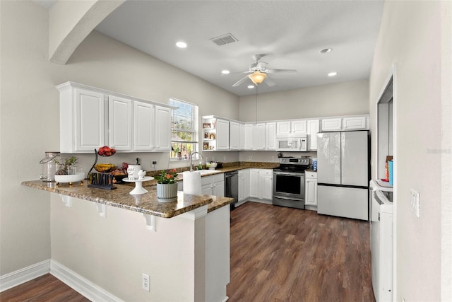 kitchen featuring sink, appliances with stainless steel finishes, white cabinetry, dark stone countertops, and kitchen peninsula