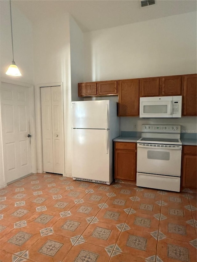 kitchen featuring a high ceiling, pendant lighting, white appliances, and light tile patterned floors