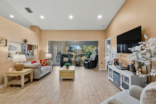 living room with light hardwood / wood-style floors and a high ceiling