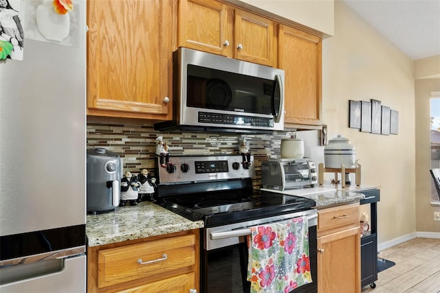 kitchen with stainless steel appliances, light stone counters, and decorative backsplash