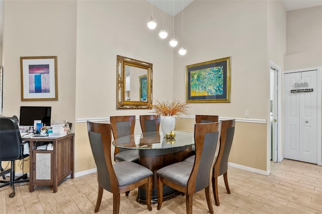 dining room with light hardwood / wood-style flooring and a high ceiling