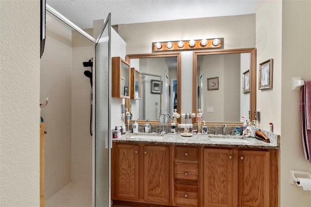 bathroom with vanity, a textured ceiling, and a tile shower