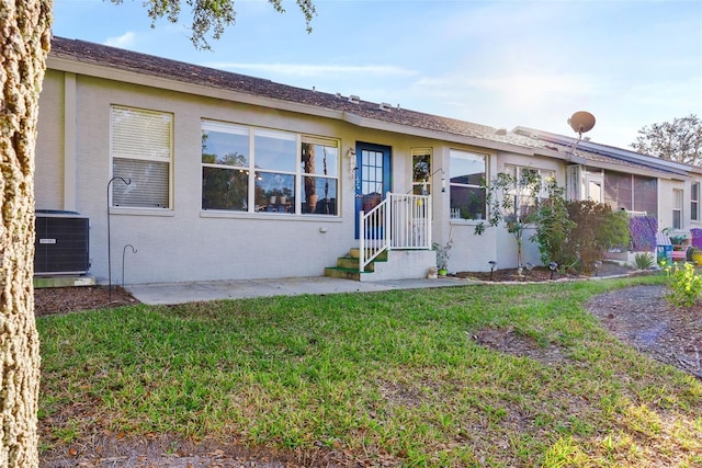 ranch-style house with a front lawn and central air condition unit