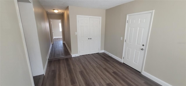 hallway with dark hardwood / wood-style floors and a textured ceiling