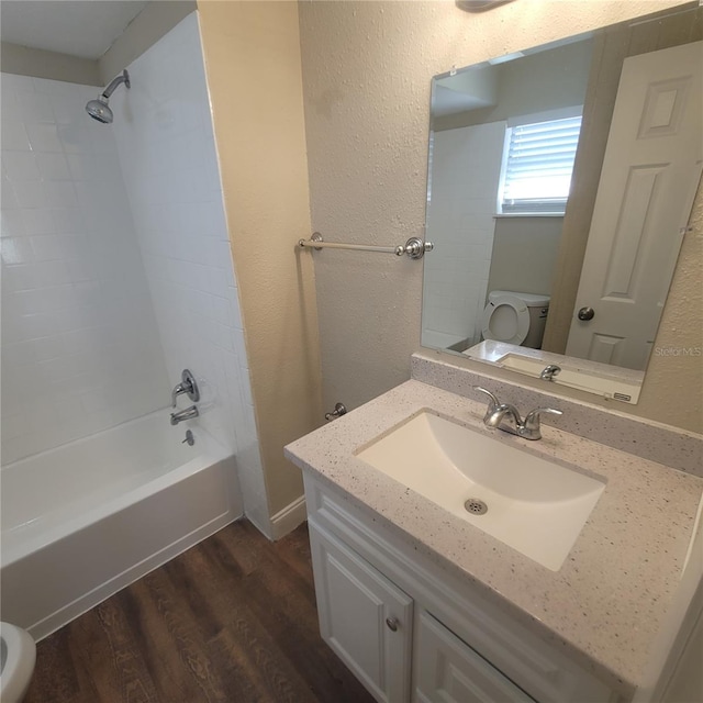 full bathroom with wood-type flooring, vanity, washtub / shower combination, and toilet