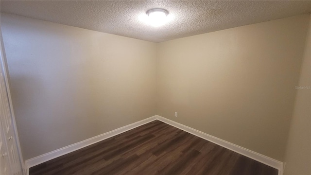 spare room featuring a textured ceiling and dark hardwood / wood-style flooring