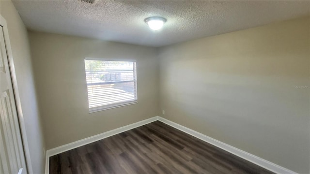 spare room with a textured ceiling and dark hardwood / wood-style flooring