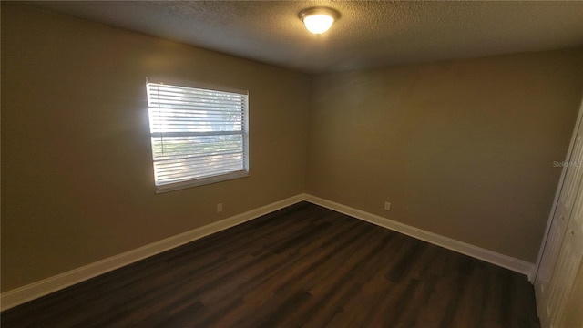 spare room featuring dark hardwood / wood-style floors and a textured ceiling