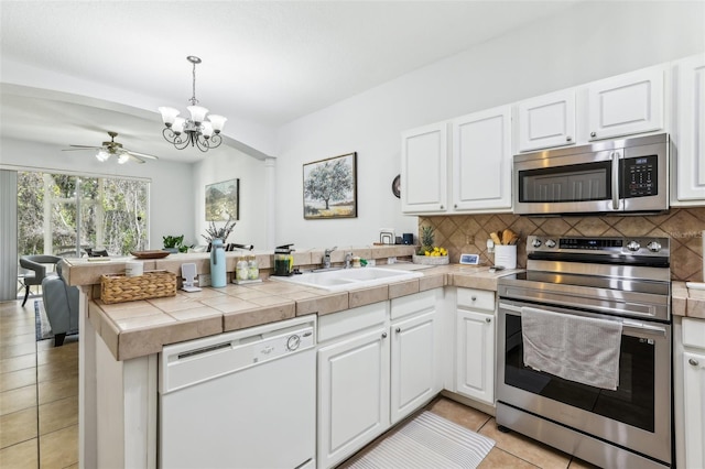 kitchen featuring stainless steel appliances, kitchen peninsula, and white cabinets