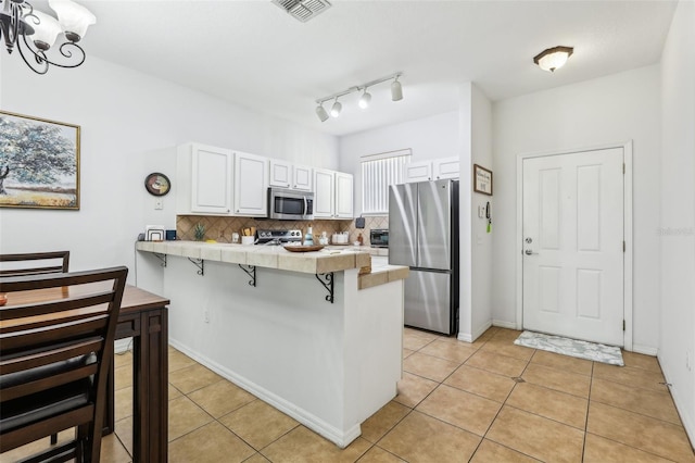 kitchen featuring appliances with stainless steel finishes, white cabinets, a kitchen bar, and kitchen peninsula