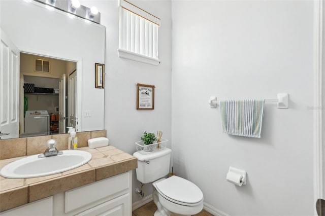 bathroom featuring toilet, vanity, and washer / clothes dryer