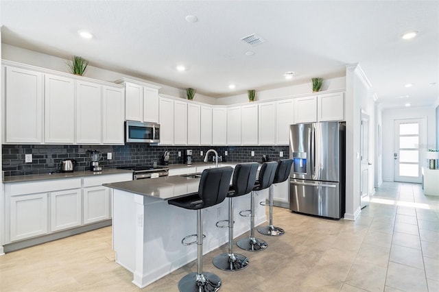 kitchen with a breakfast bar, sink, a center island with sink, appliances with stainless steel finishes, and white cabinets