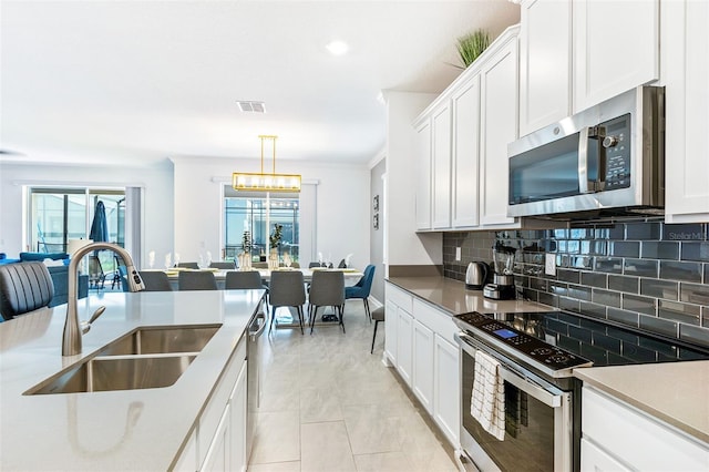 kitchen featuring white cabinetry, sink, hanging light fixtures, and appliances with stainless steel finishes