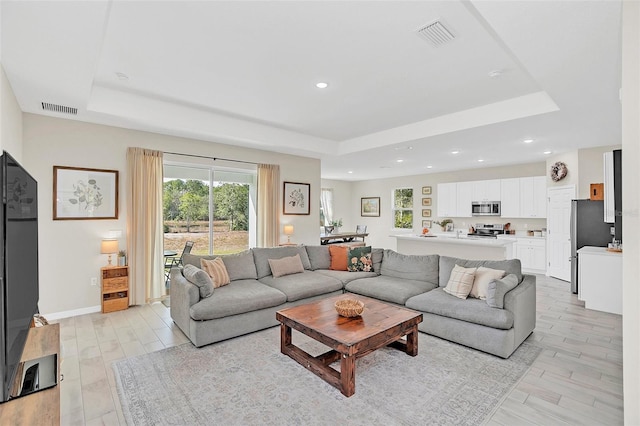 living room with a raised ceiling and light hardwood / wood-style floors