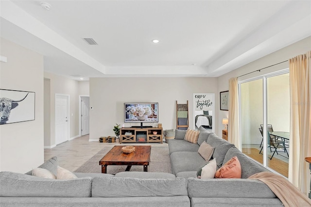 living room with a tray ceiling and light hardwood / wood-style floors