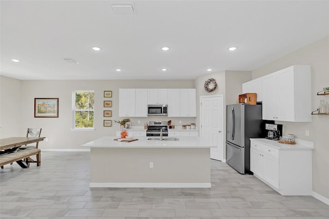 kitchen featuring appliances with stainless steel finishes, sink, a kitchen island with sink, and white cabinets