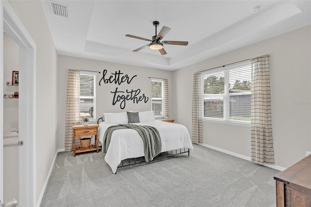 carpeted bedroom featuring a raised ceiling and ceiling fan