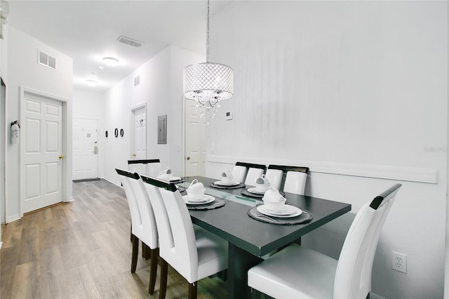 dining room with hardwood / wood-style flooring, a notable chandelier, and electric panel