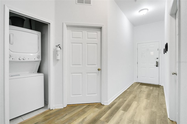 laundry room with stacked washer / dryer and light wood-type flooring