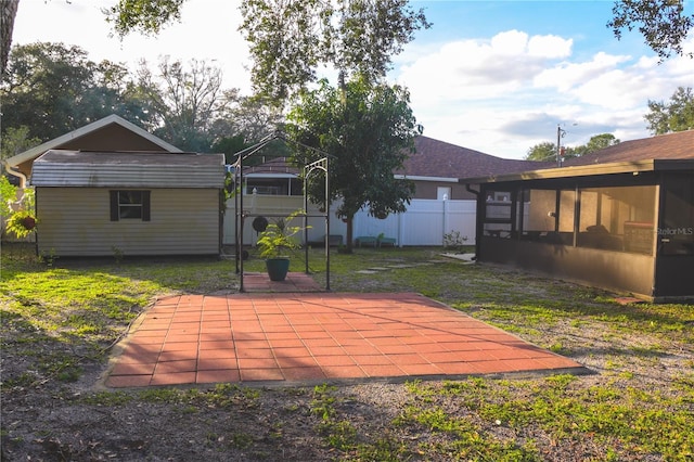 back of property featuring a patio, a sunroom, a lawn, and a storage unit