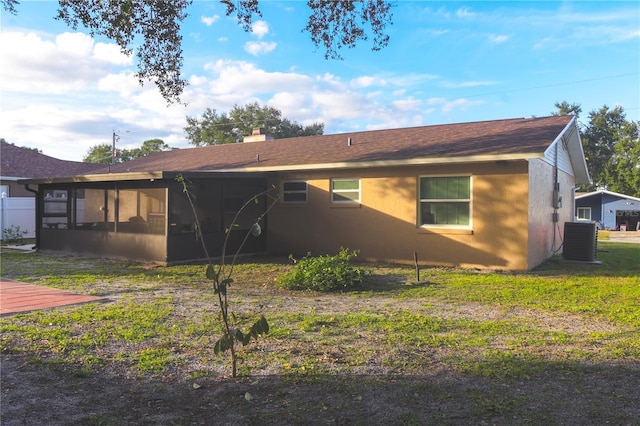 rear view of house featuring a sunroom, central AC, and a lawn