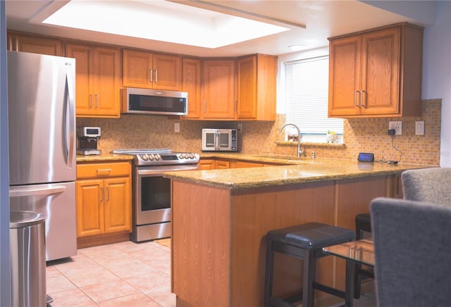 kitchen featuring sink, light tile patterned floors, light stone counters, kitchen peninsula, and stainless steel appliances