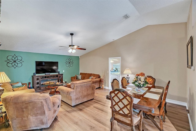 living room featuring ceiling fan, lofted ceiling, a textured ceiling, and light wood-type flooring