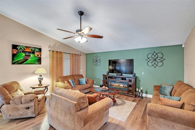 living room with ceiling fan, lofted ceiling, a textured ceiling, and light hardwood / wood-style floors