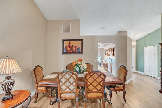 dining area with sink, light hardwood / wood-style flooring, and a textured ceiling