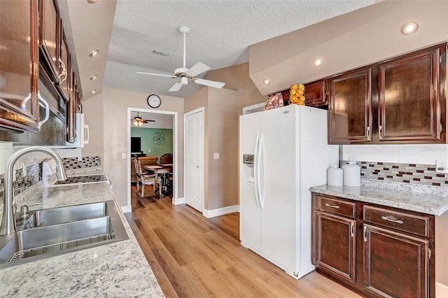 kitchen featuring sink, ceiling fan, backsplash, white fridge with ice dispenser, and light wood-type flooring