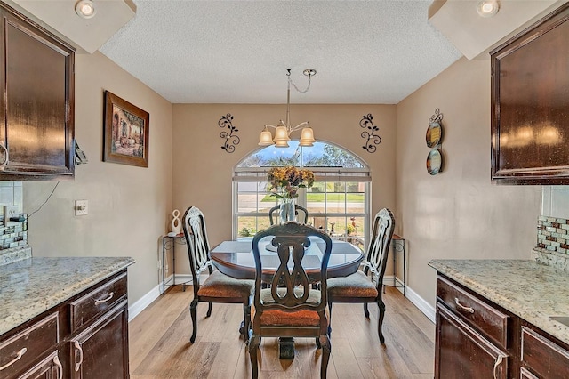 dining room featuring an inviting chandelier, a textured ceiling, and light wood-type flooring