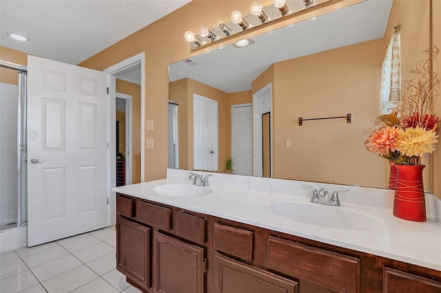 bathroom featuring tile patterned flooring, vanity, a textured ceiling, and a shower with shower door