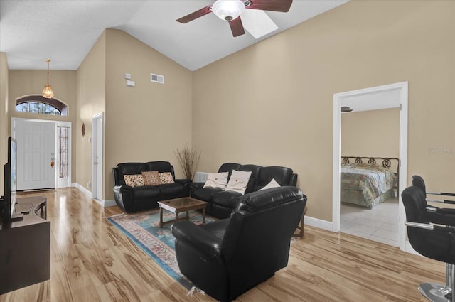 living room featuring high vaulted ceiling, light hardwood / wood-style floors, and ceiling fan