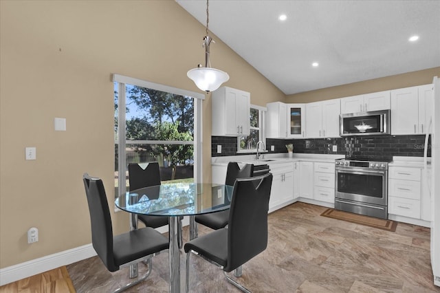 kitchen with sink, white cabinetry, tasteful backsplash, hanging light fixtures, and appliances with stainless steel finishes