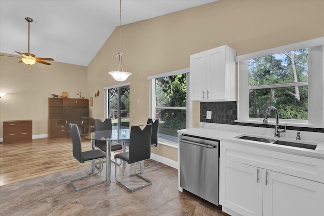 kitchen with pendant lighting, sink, dishwasher, light stone counters, and white cabinets