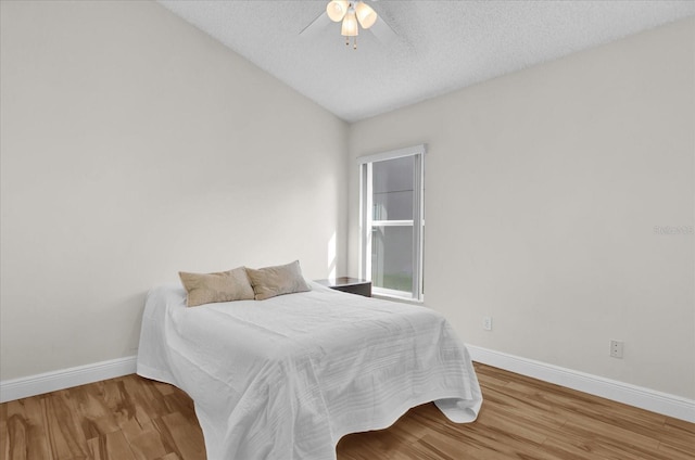 bedroom with hardwood / wood-style floors, a textured ceiling, vaulted ceiling, and ceiling fan