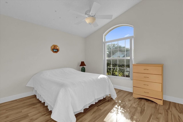 bedroom with ceiling fan, lofted ceiling, and light hardwood / wood-style flooring