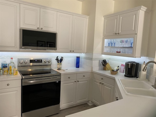 kitchen with stainless steel appliances, tasteful backsplash, sink, and white cabinets