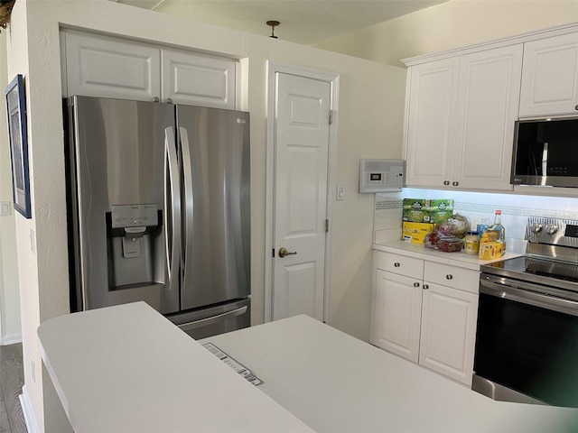 kitchen featuring white cabinetry, decorative light fixtures, tasteful backsplash, and stainless steel appliances