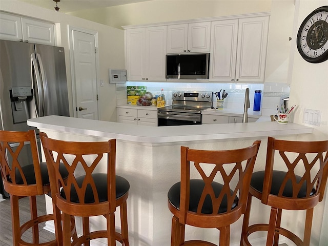 kitchen featuring white cabinetry, appliances with stainless steel finishes, and a kitchen breakfast bar