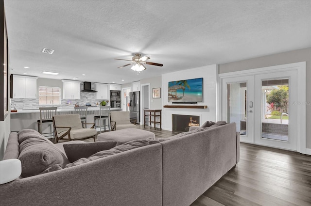 living room with french doors, ceiling fan, dark hardwood / wood-style flooring, and a textured ceiling