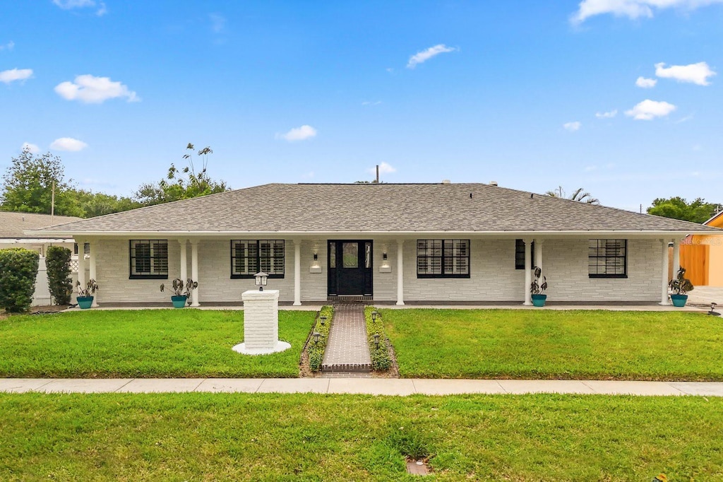 3010 Bay Tree Dr, Orlando, FL 32806 - ranch-style house featuring a front yard, a porch, brick siding, and roof with shingles