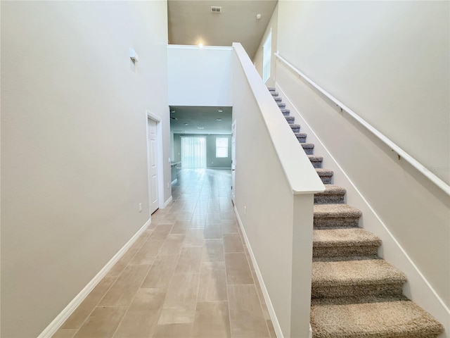 stairway featuring a towering ceiling