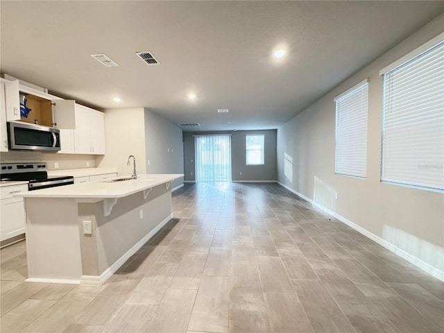 kitchen featuring white cabinetry, stainless steel appliances, sink, and an island with sink