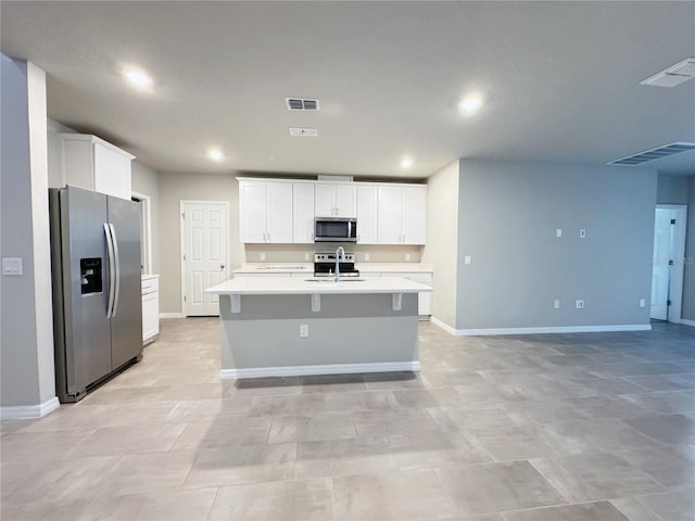 kitchen with an island with sink, appliances with stainless steel finishes, sink, and white cabinets